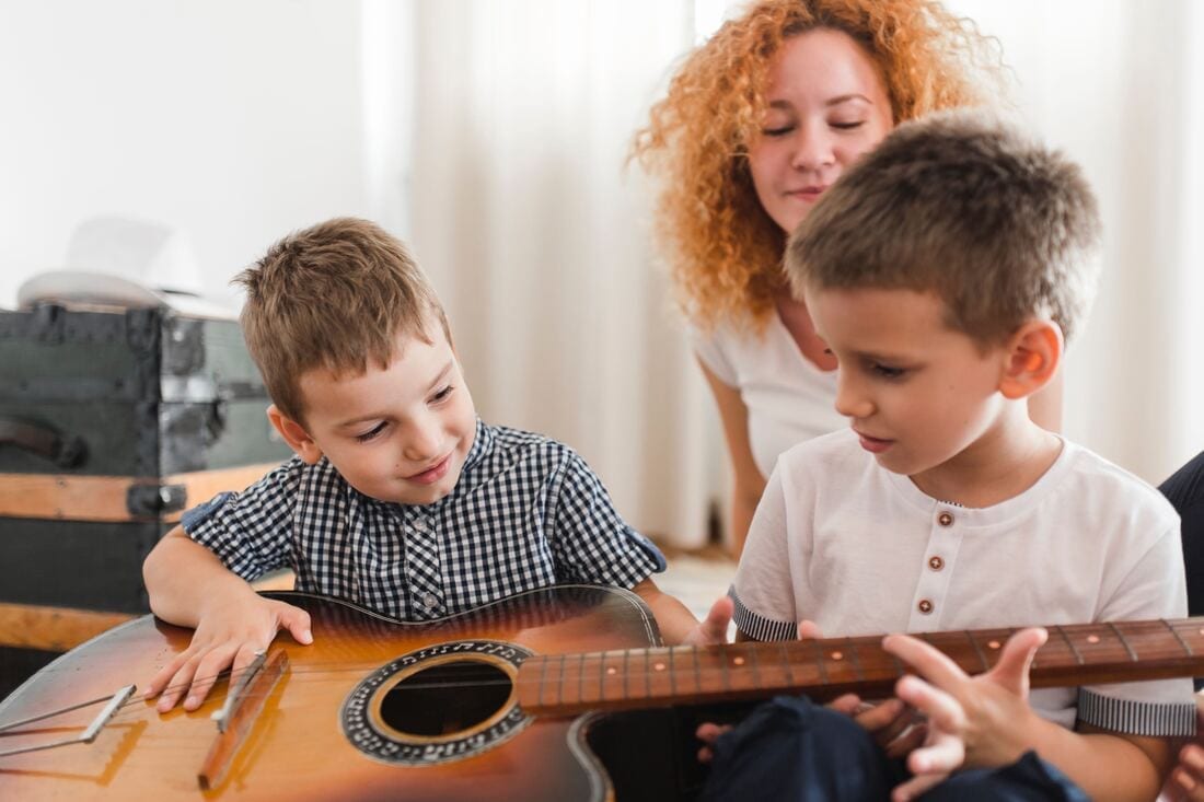 Two boys play with guitar in a therapy session