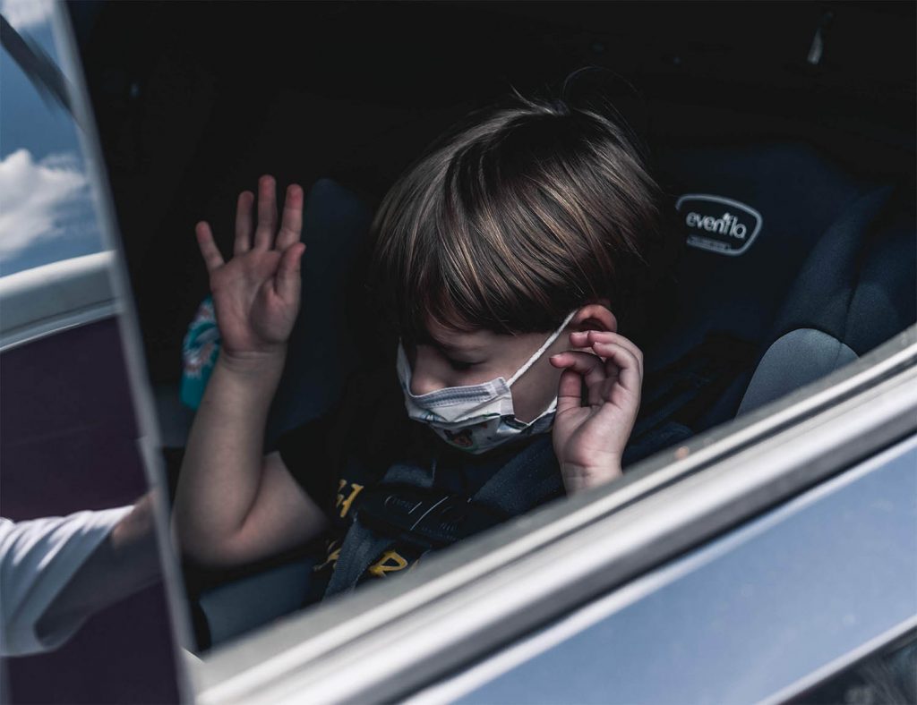 Young boy practices getting in and out of their car seat before a journey