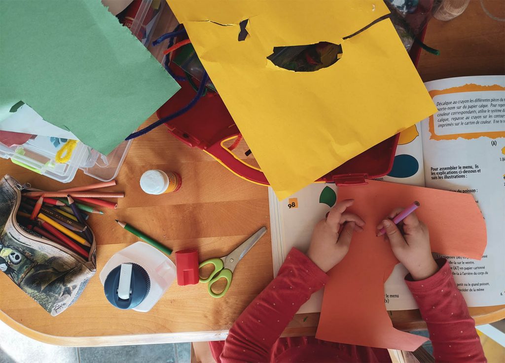 Child creating a scrap book from colourful pieces of paper and other items