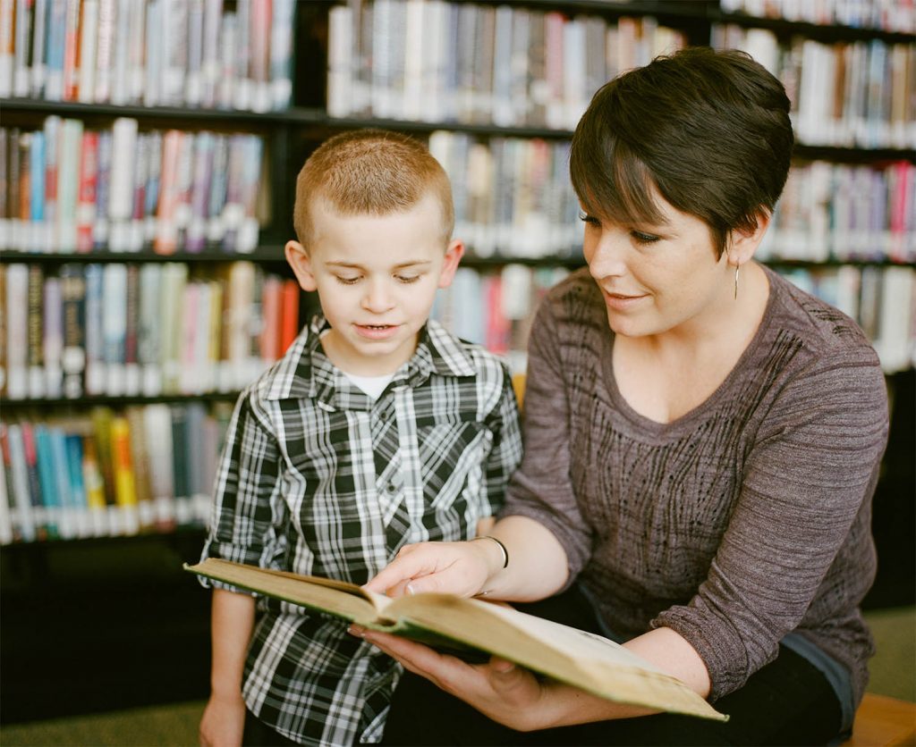 Mum and child read a book to learn about their holiday destination